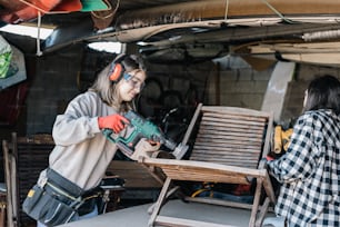 two women are working on a piece of furniture