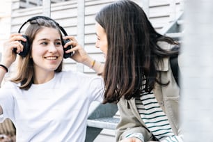 two girls sitting on a bench with headphones on