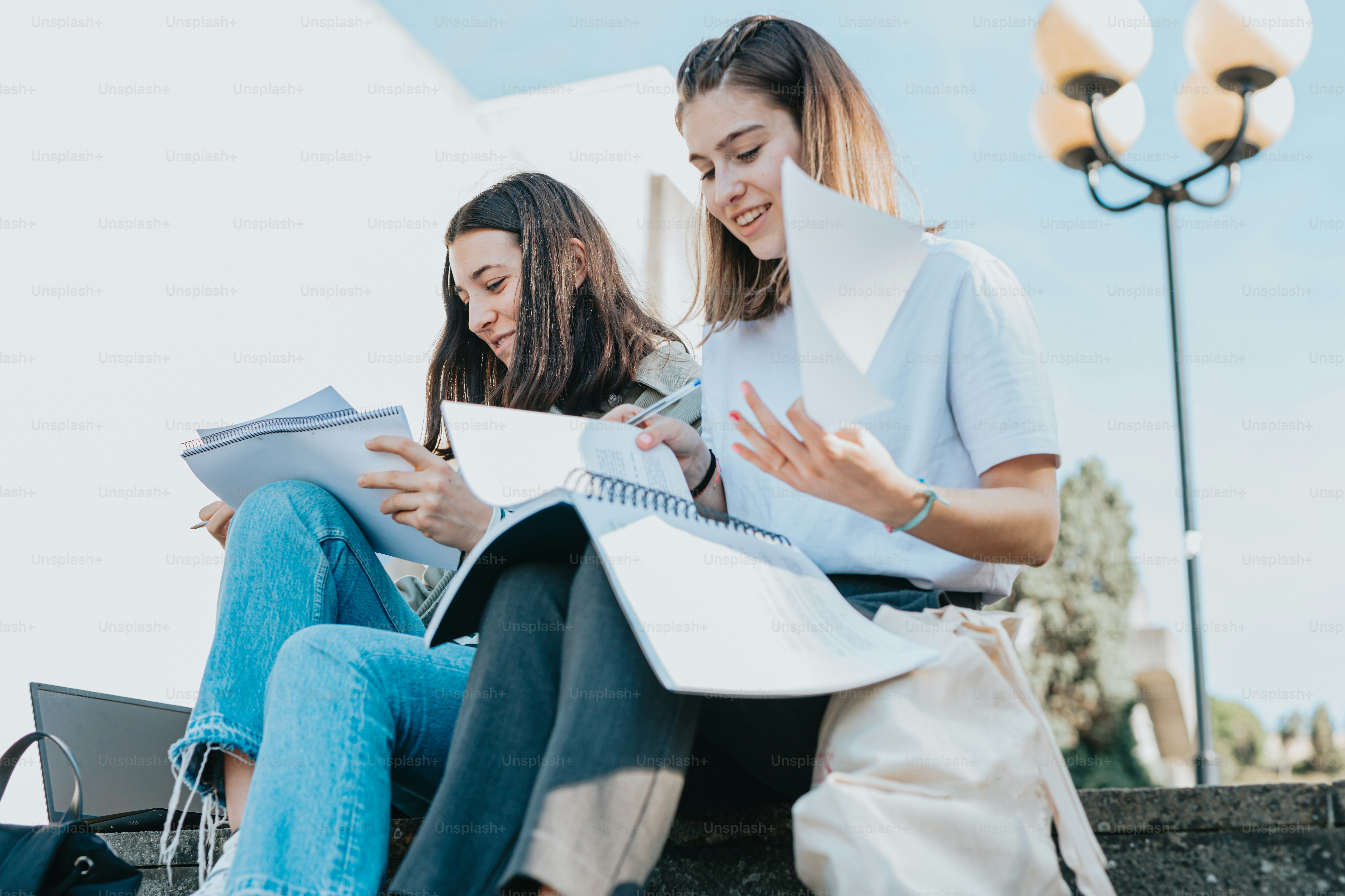 two young women sitting on the steps of a building