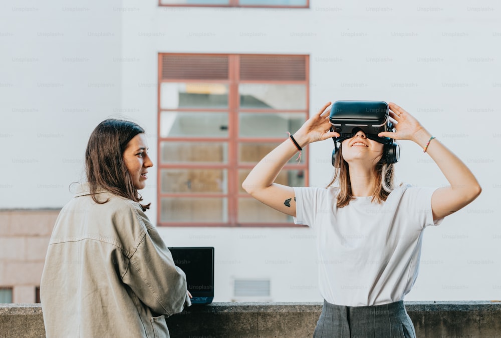 duas mulheres de pé uma ao lado da outra olhando através de um par de óculos virtuais