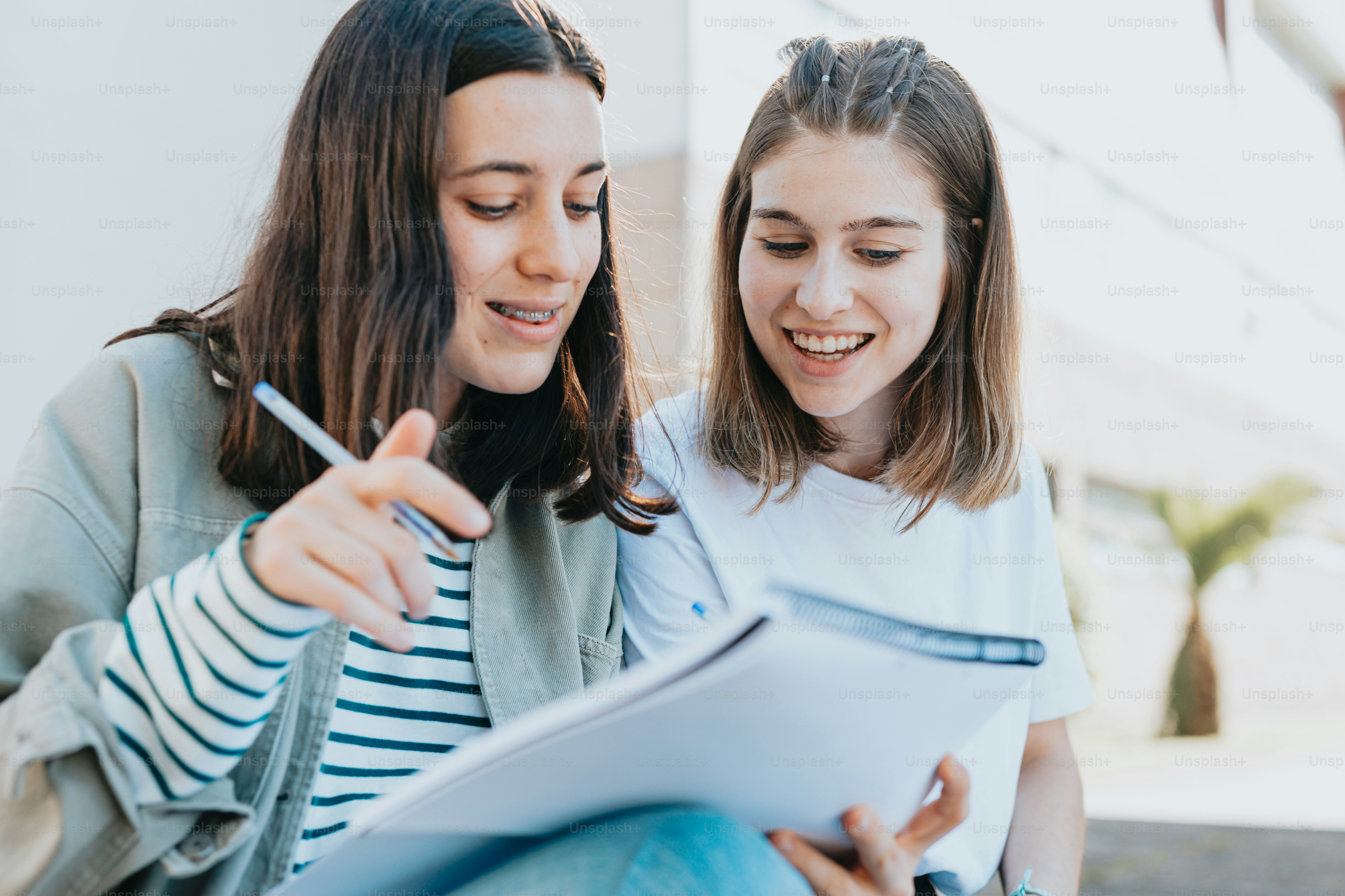 two girls sitting on the ground looking at a piece of paper