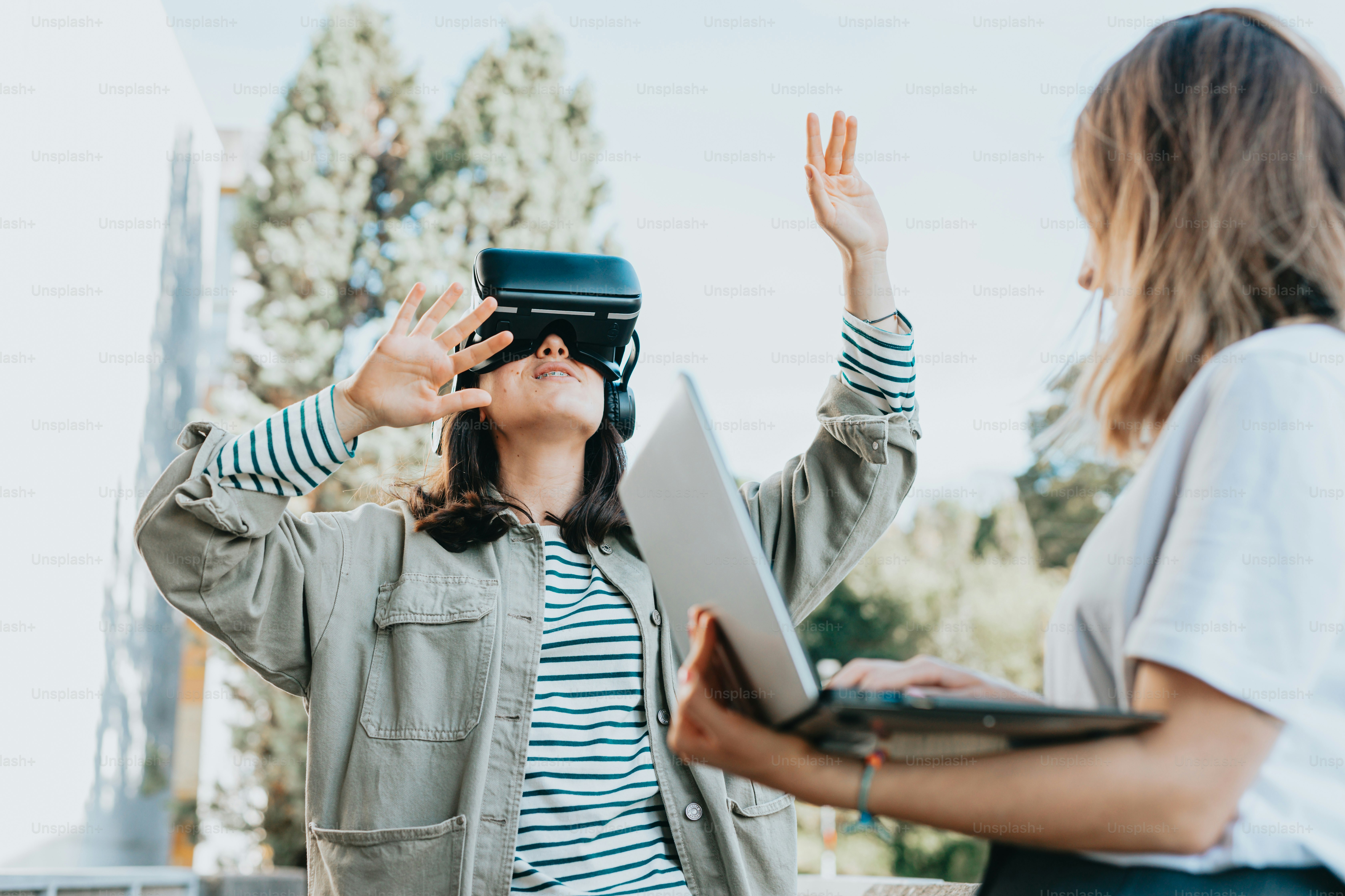 two women standing next to each other holding a laptop