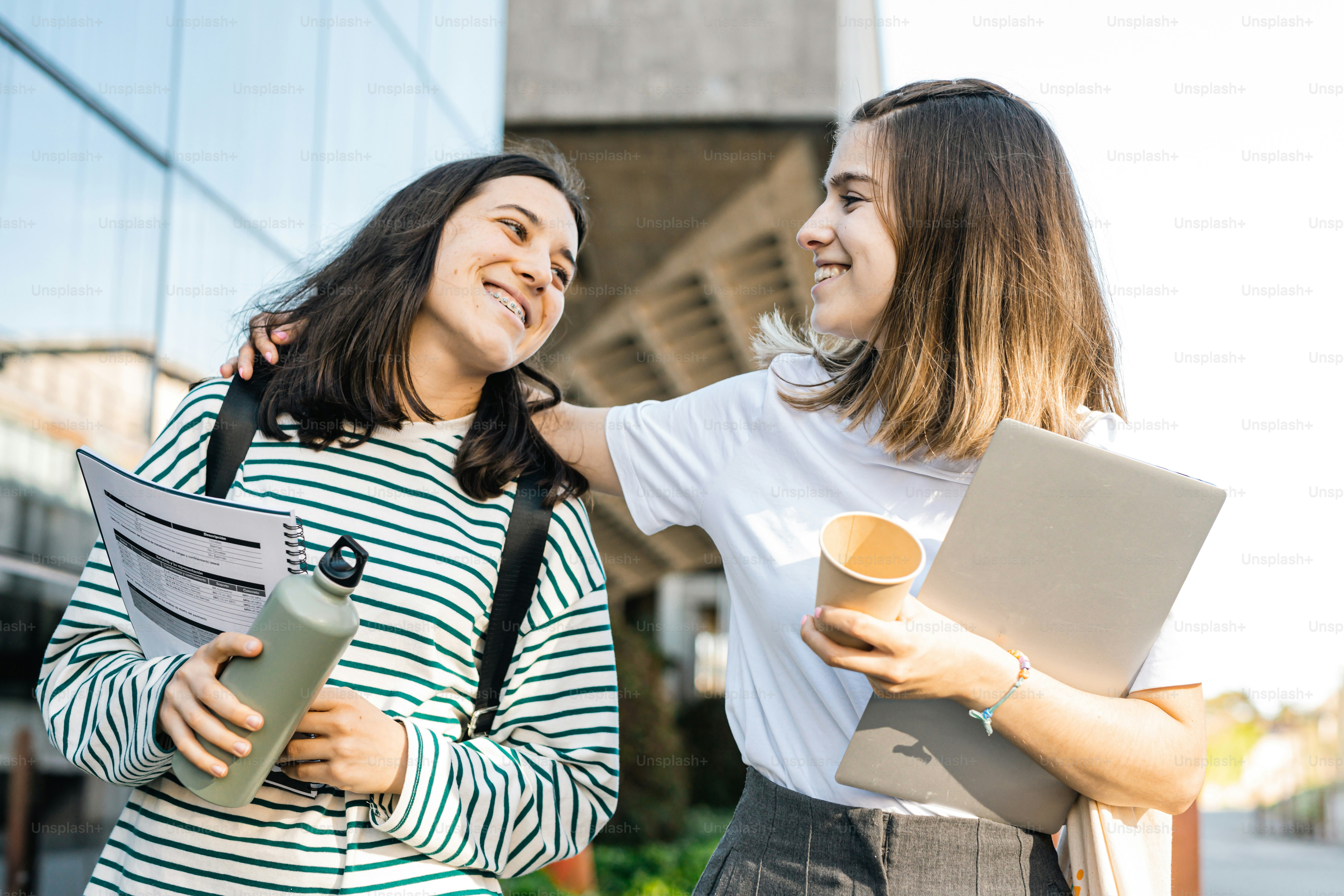 two women standing next to each other holding papers