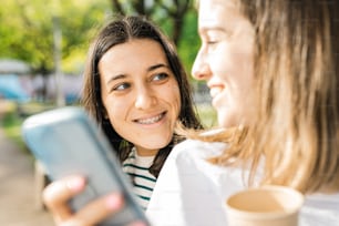 two women smiling and looking at a cell phone