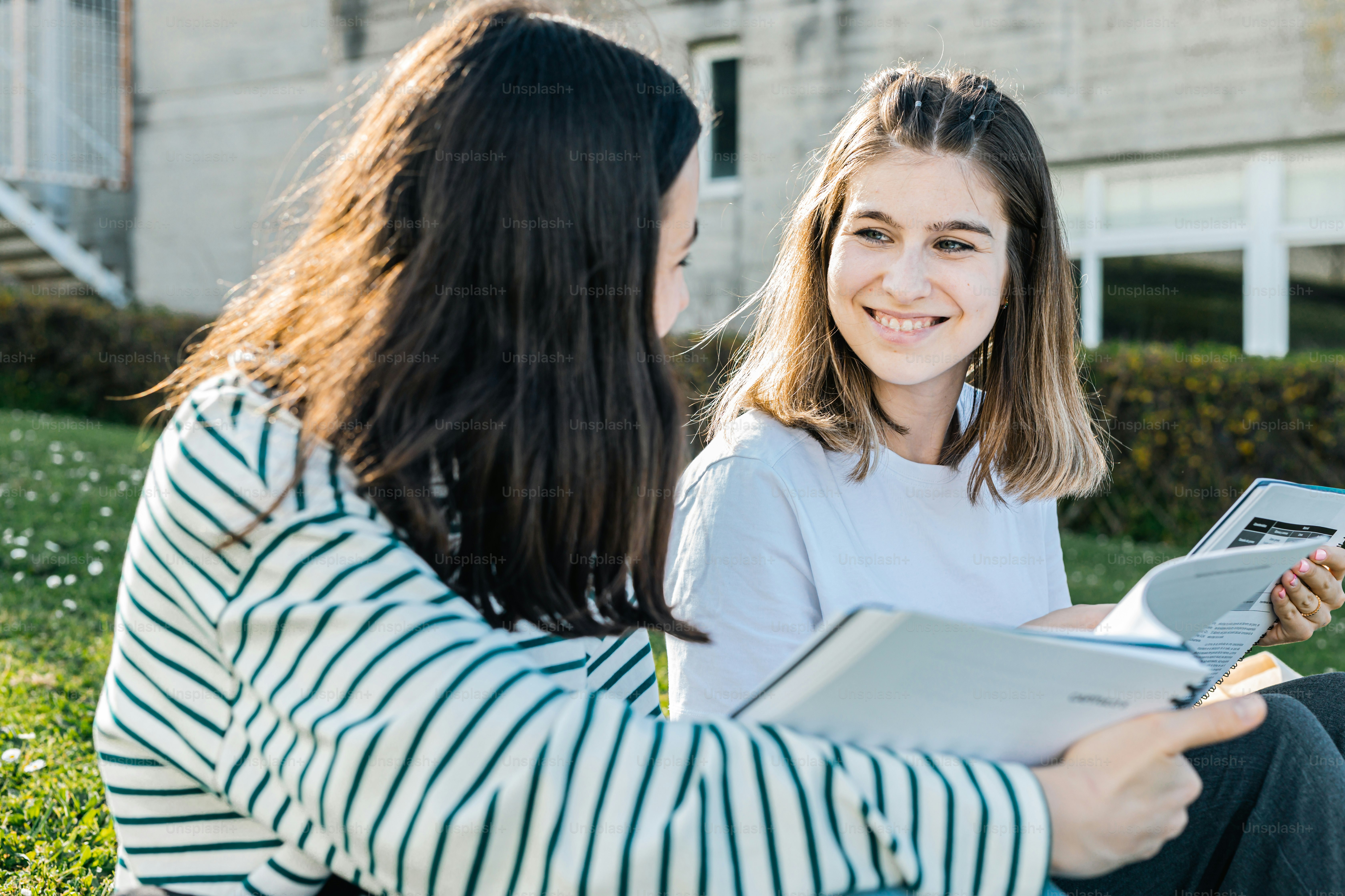 two women sitting on the grass talking to each other