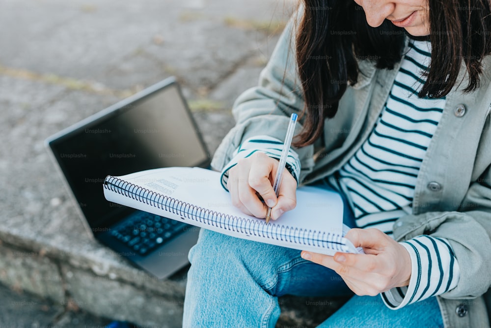 a woman sitting on steps writing on a notebook