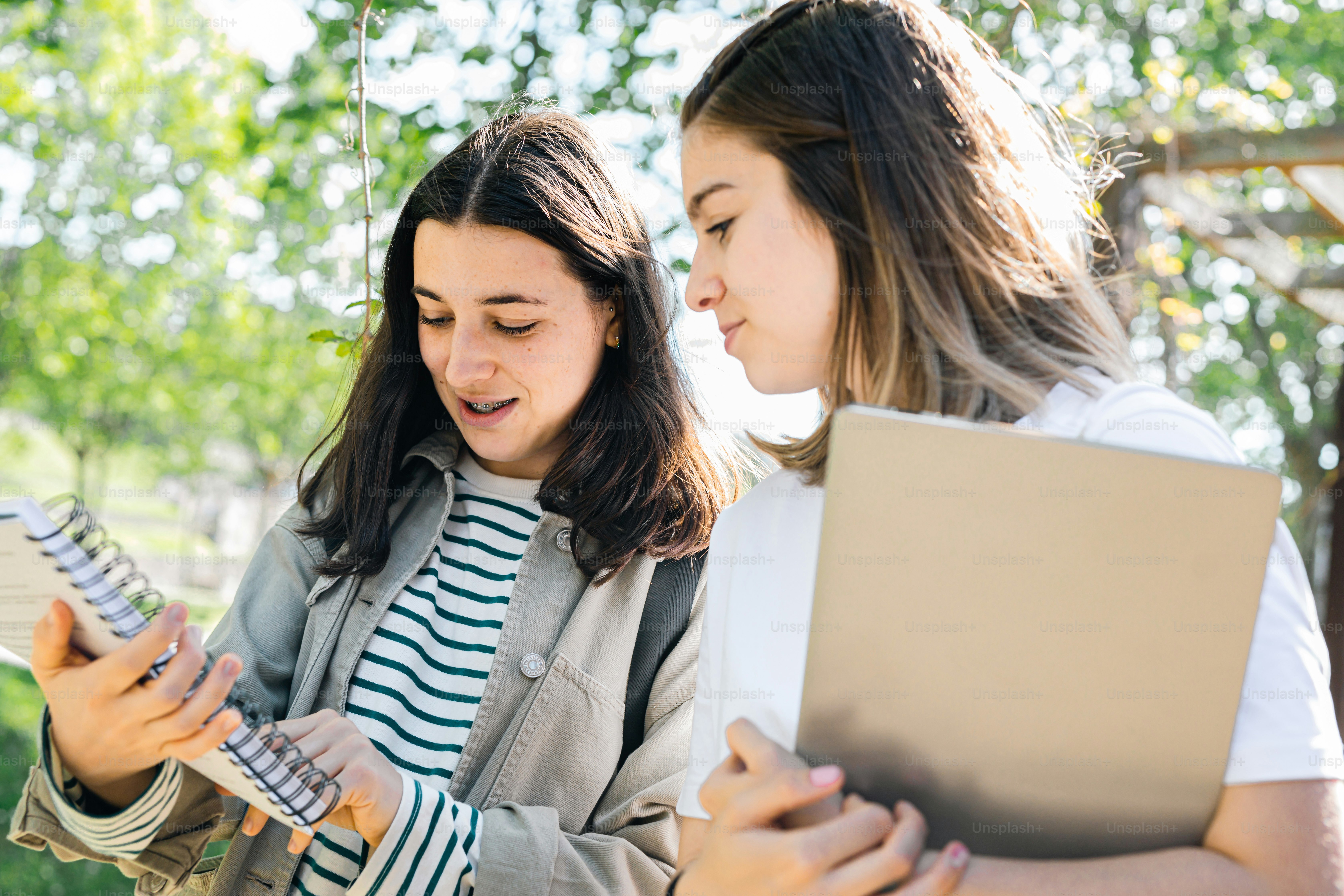 two girls are looking at a book together