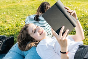 草の上に横たわって本を読む女性