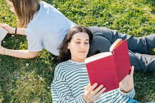 a woman laying on the ground reading a book