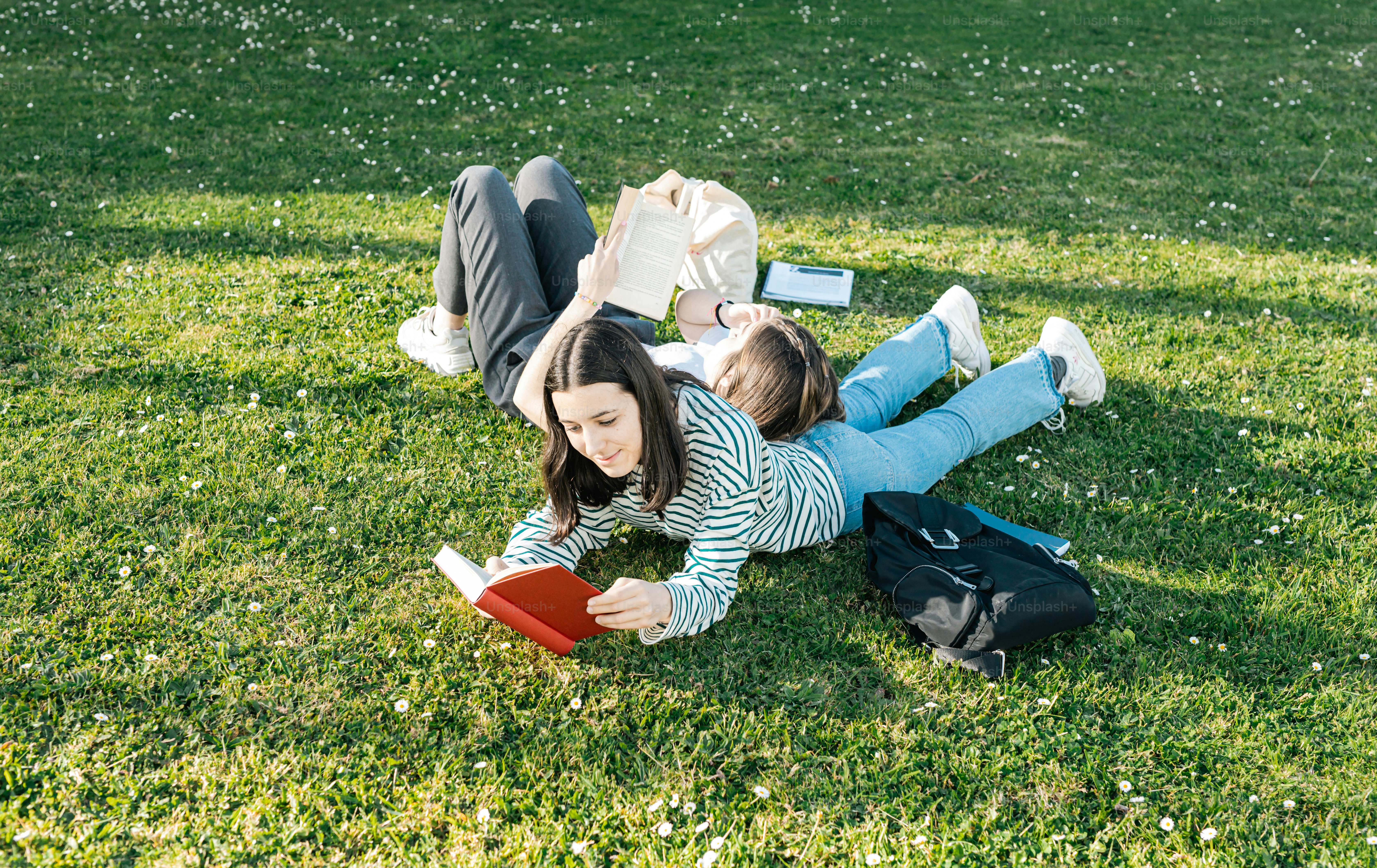 a woman laying on the grass reading a book