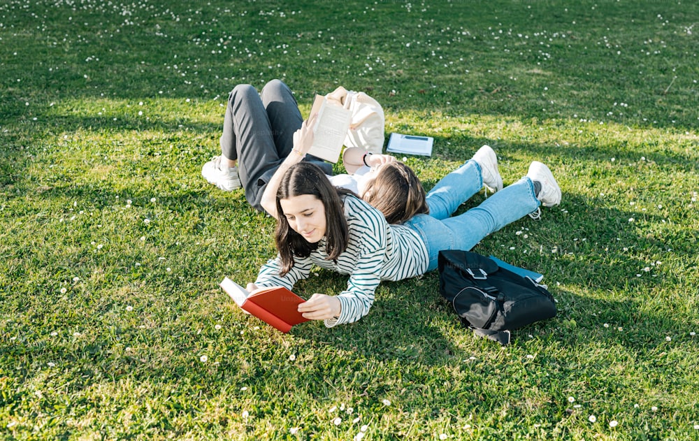 a woman laying on the grass reading a book