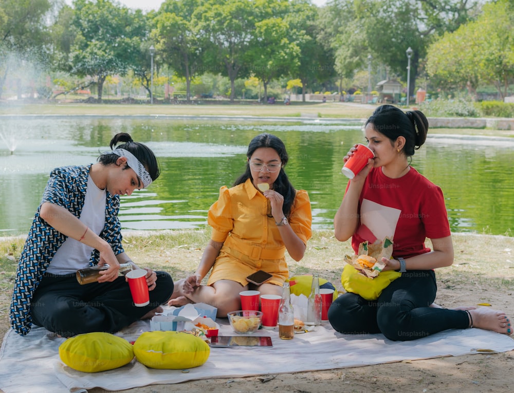 Eine Gruppe von Frauen, die auf einer Decke neben einem See sitzen