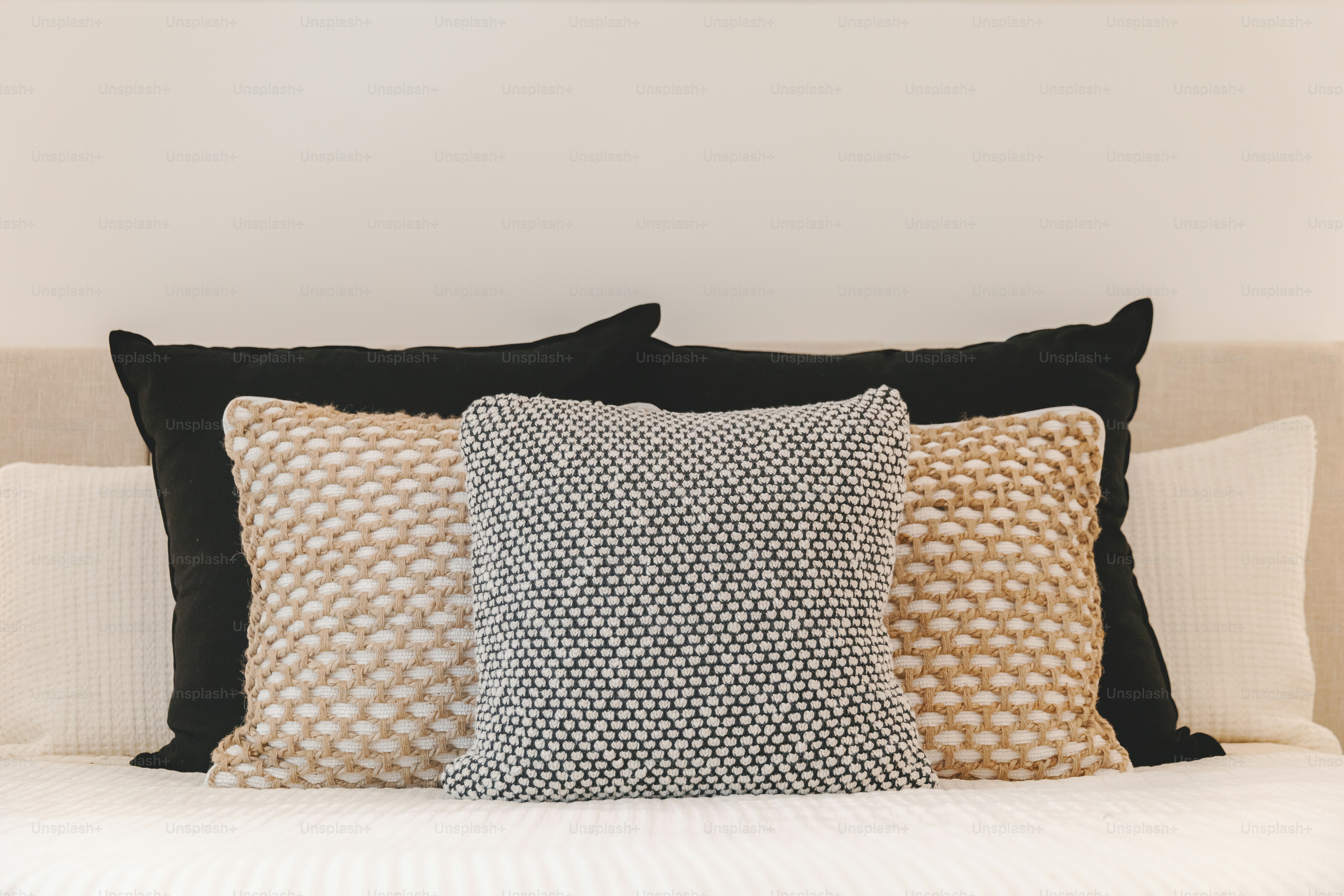 una cama cubierta con muchas almohadas al lado de una pared