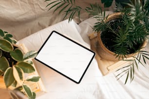 a tablet computer sitting on top of a table next to a potted plant