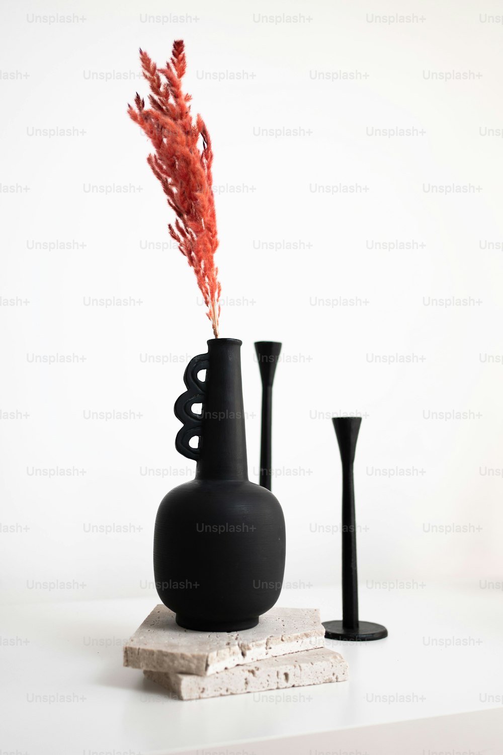 eine schwarze Vase, die auf einem weißen Tisch sitzt