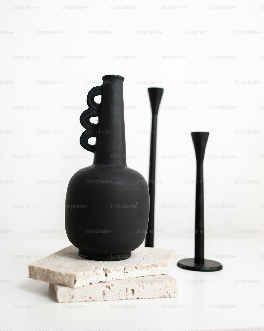 a black vase sitting on top of a white table