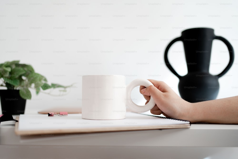a person holding a coffee mug on top of a table