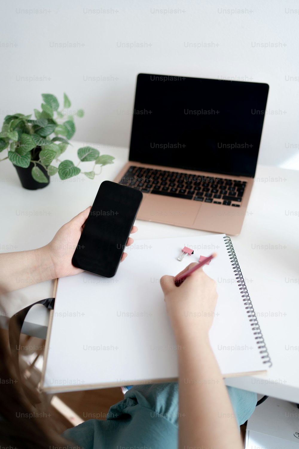 a woman sitting at a desk writing on a notepad