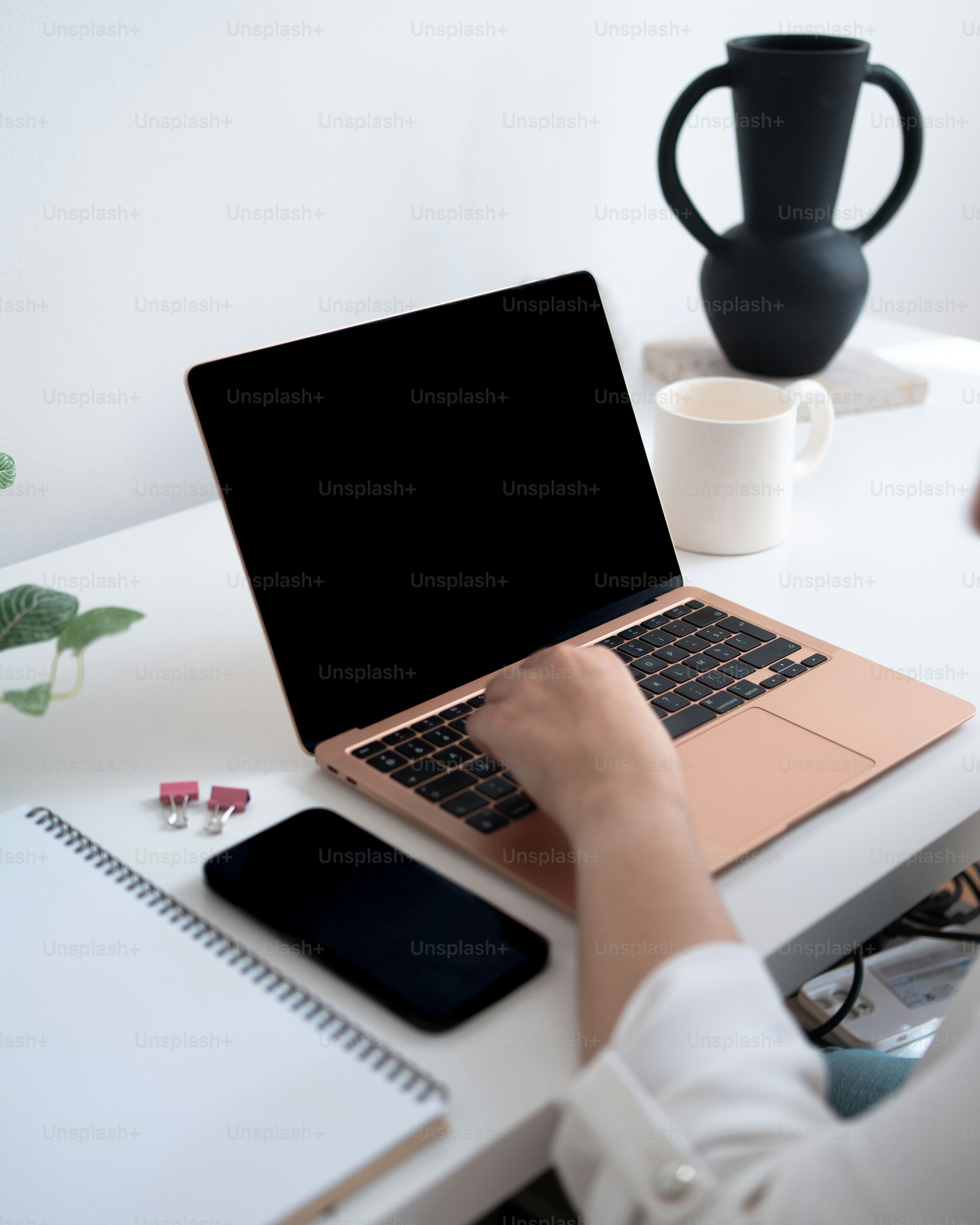 a person sitting at a desk with a laptop and cell phone
