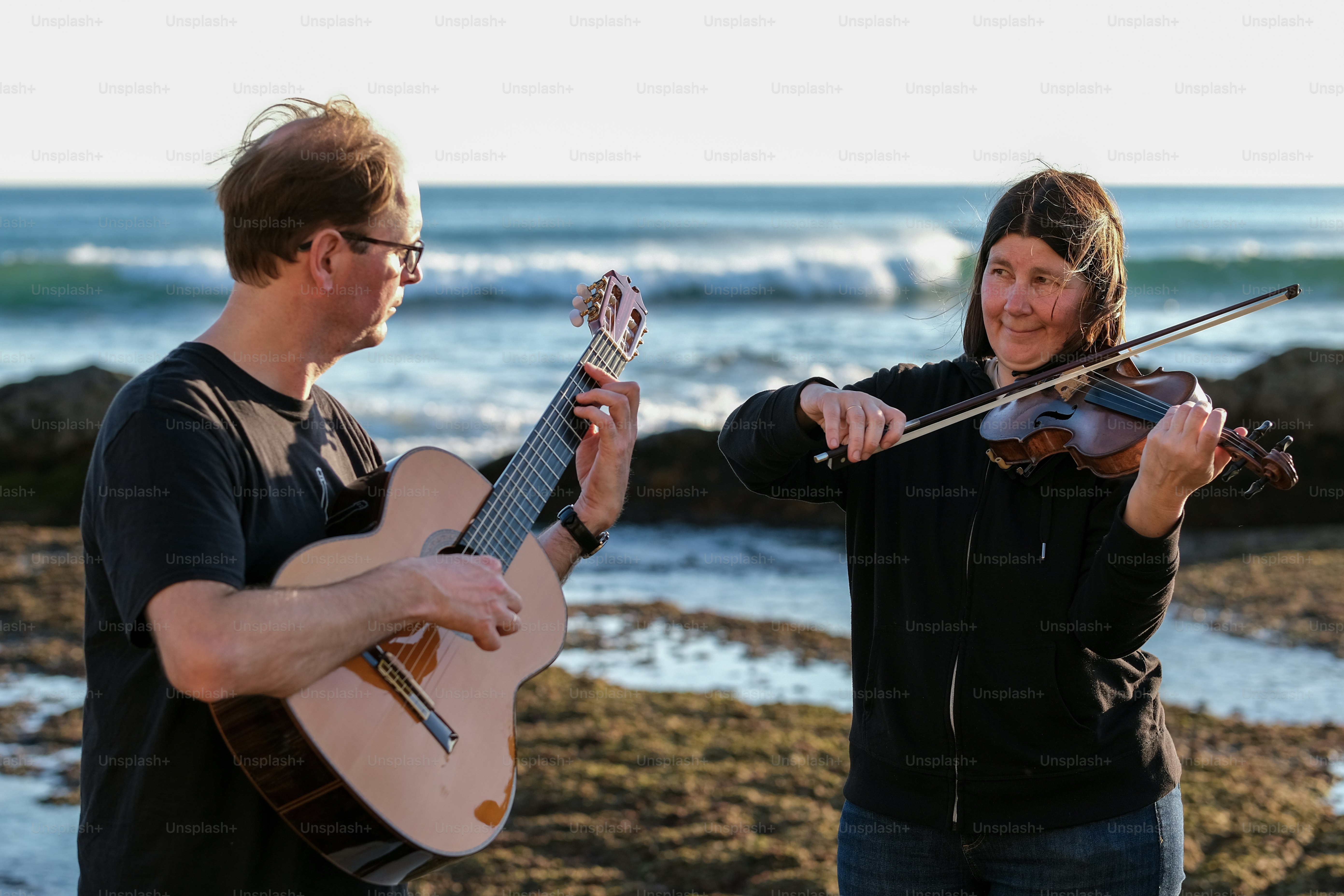 a man playing a violin next to a woman
