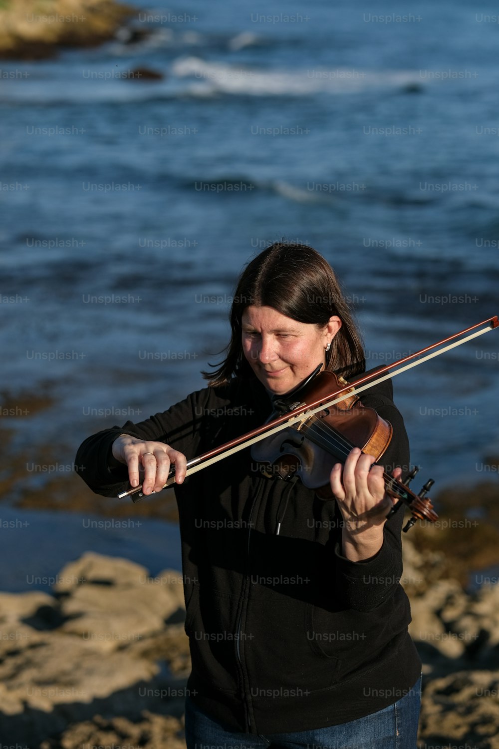 a woman playing a violin on the beach