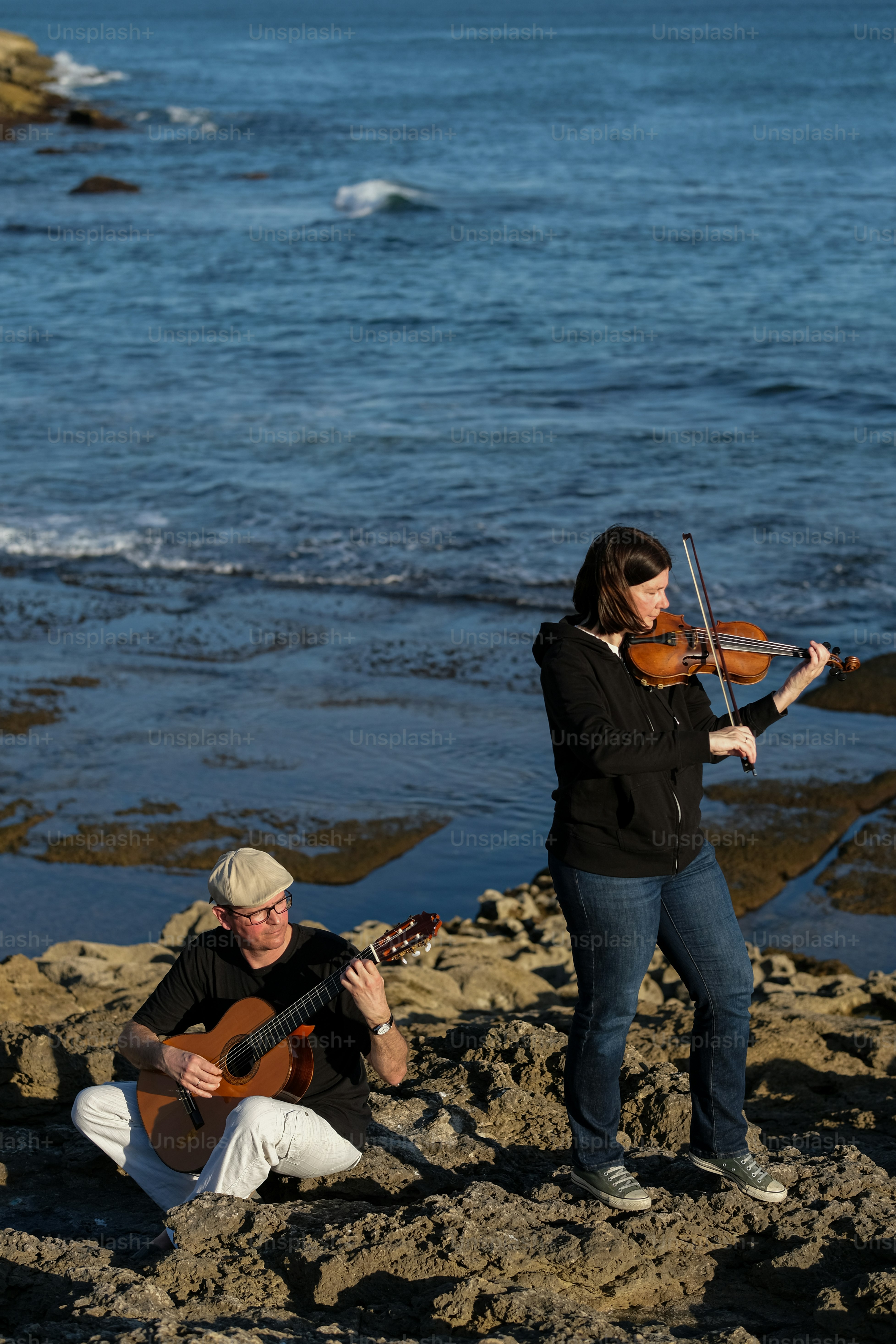 a woman playing a violin next to a man playing a guitar