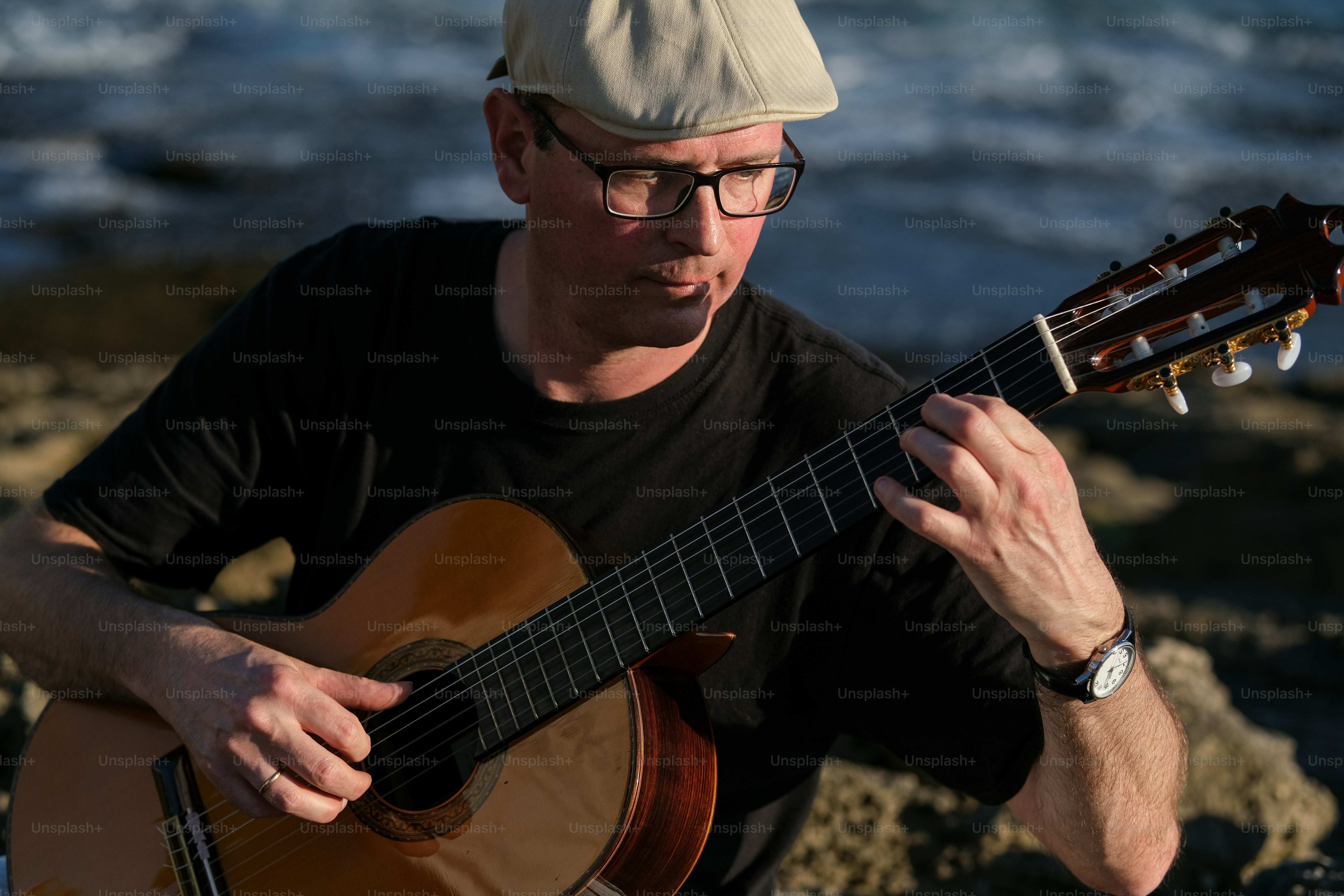 a man playing a guitar on the beach
