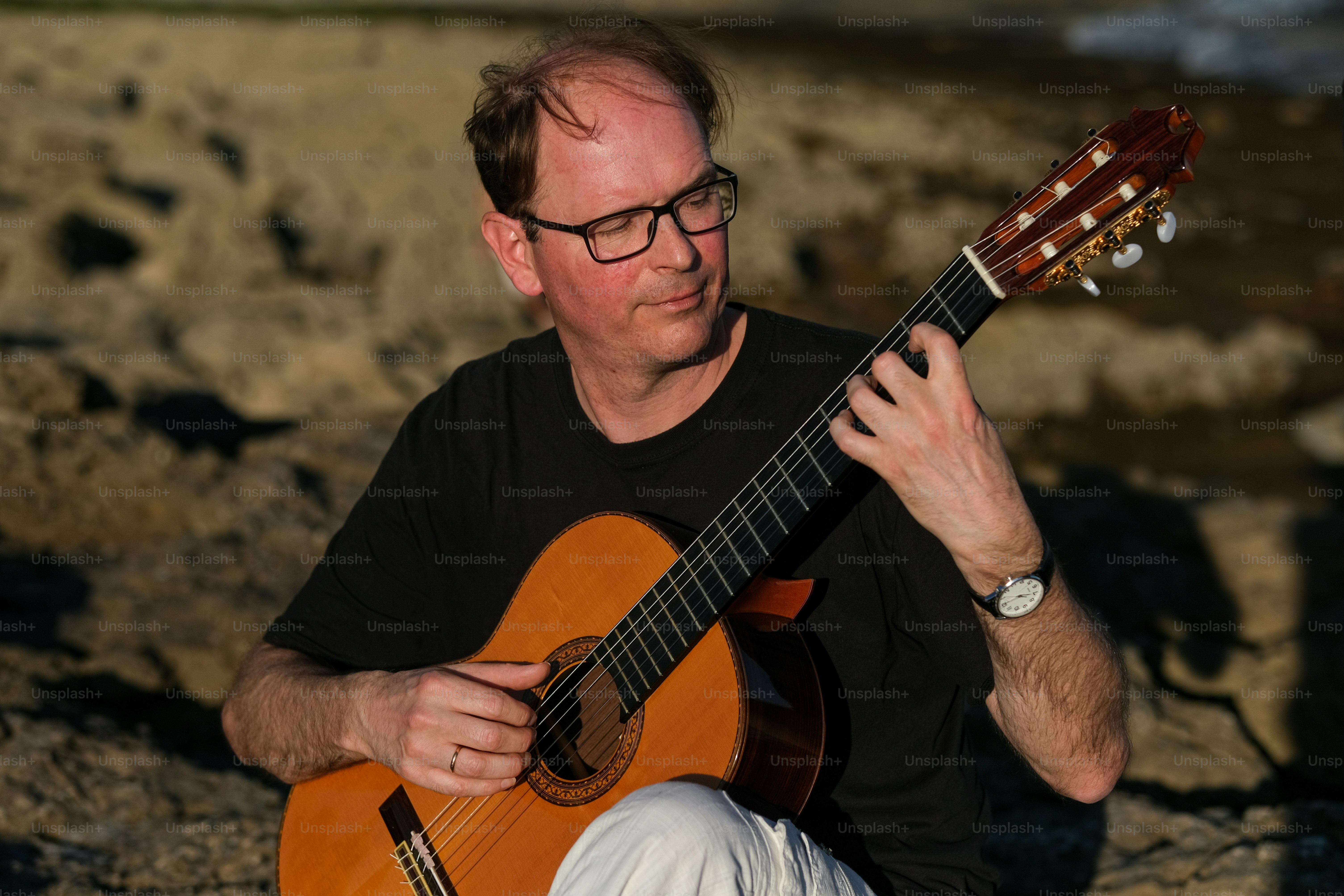a man sitting on a rock playing a guitar