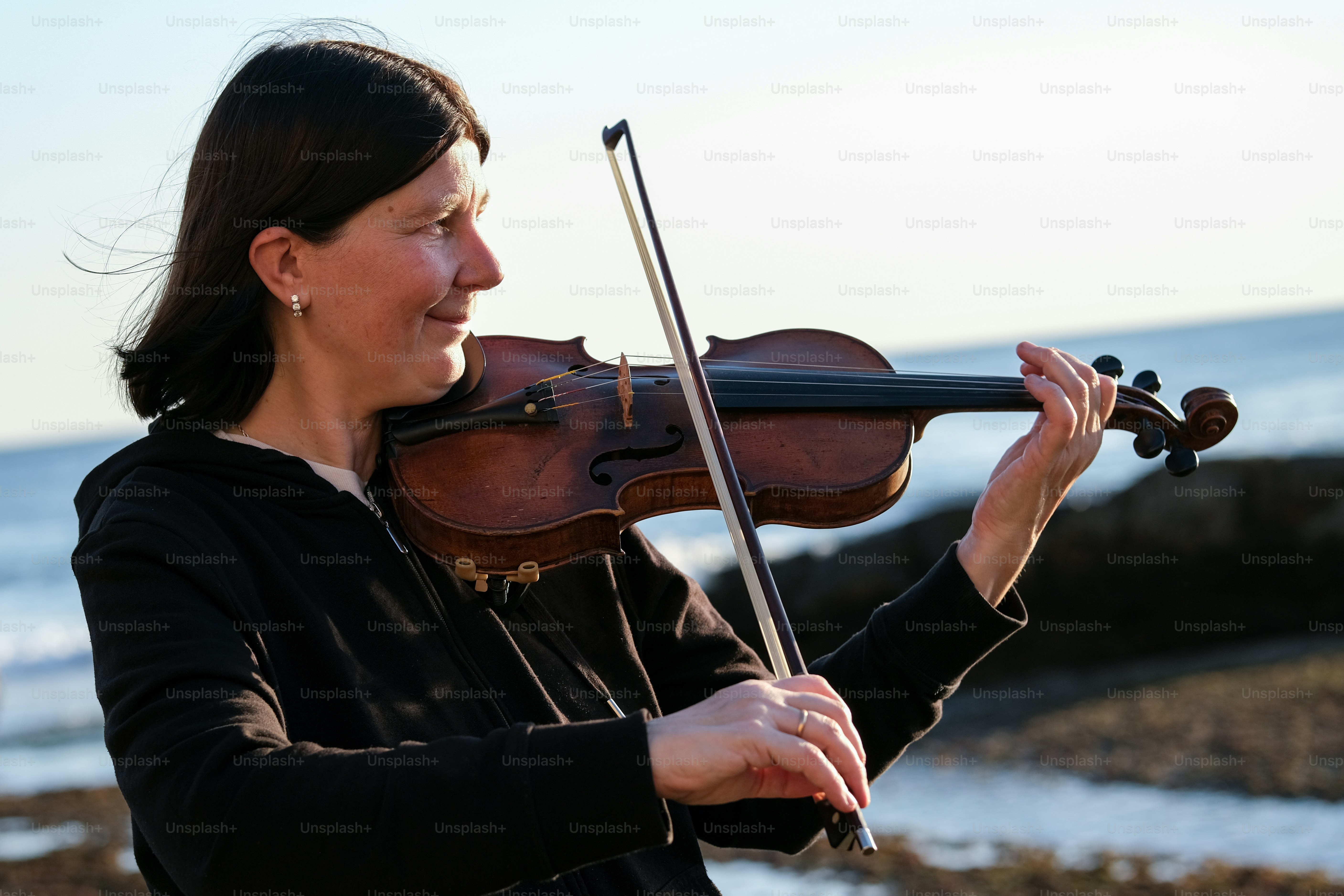 a woman playing a violin on the beach