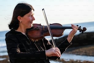 Una mujer tocando un violín en la playa
