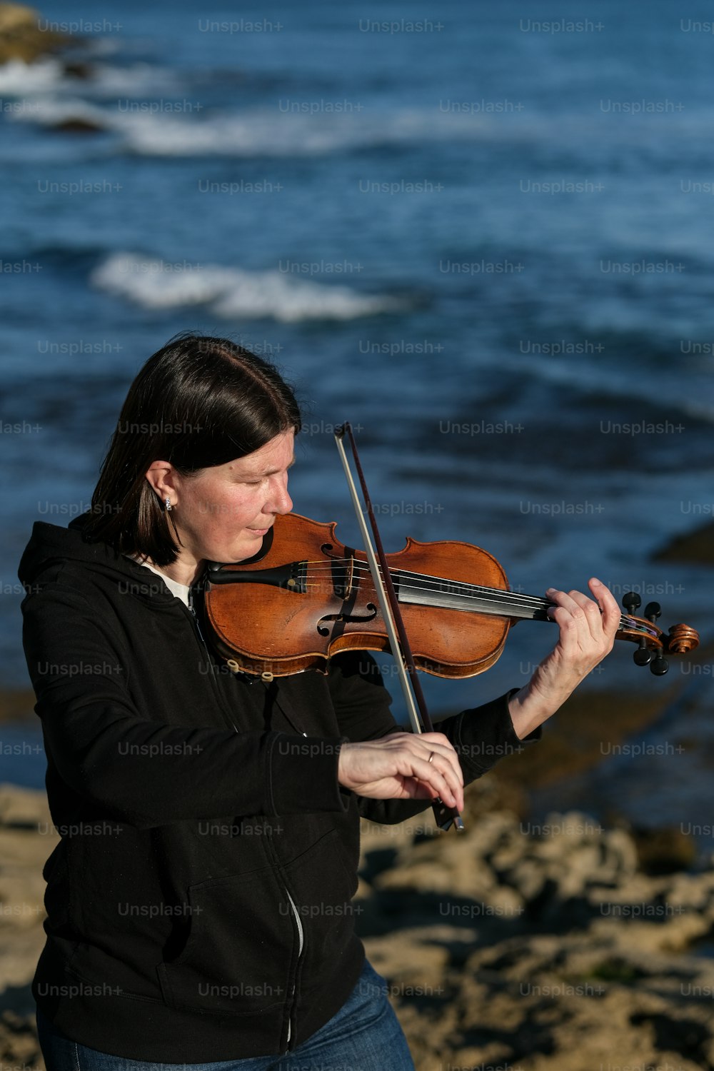 a woman playing a violin on the beach