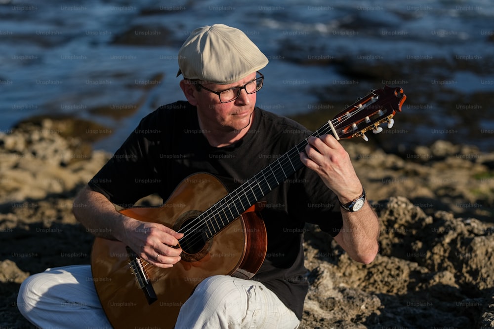a man sitting on a rock playing a guitar