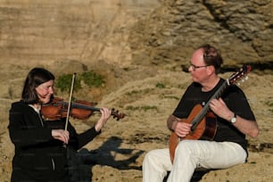 Un hombre tocando un violín junto a una mujer