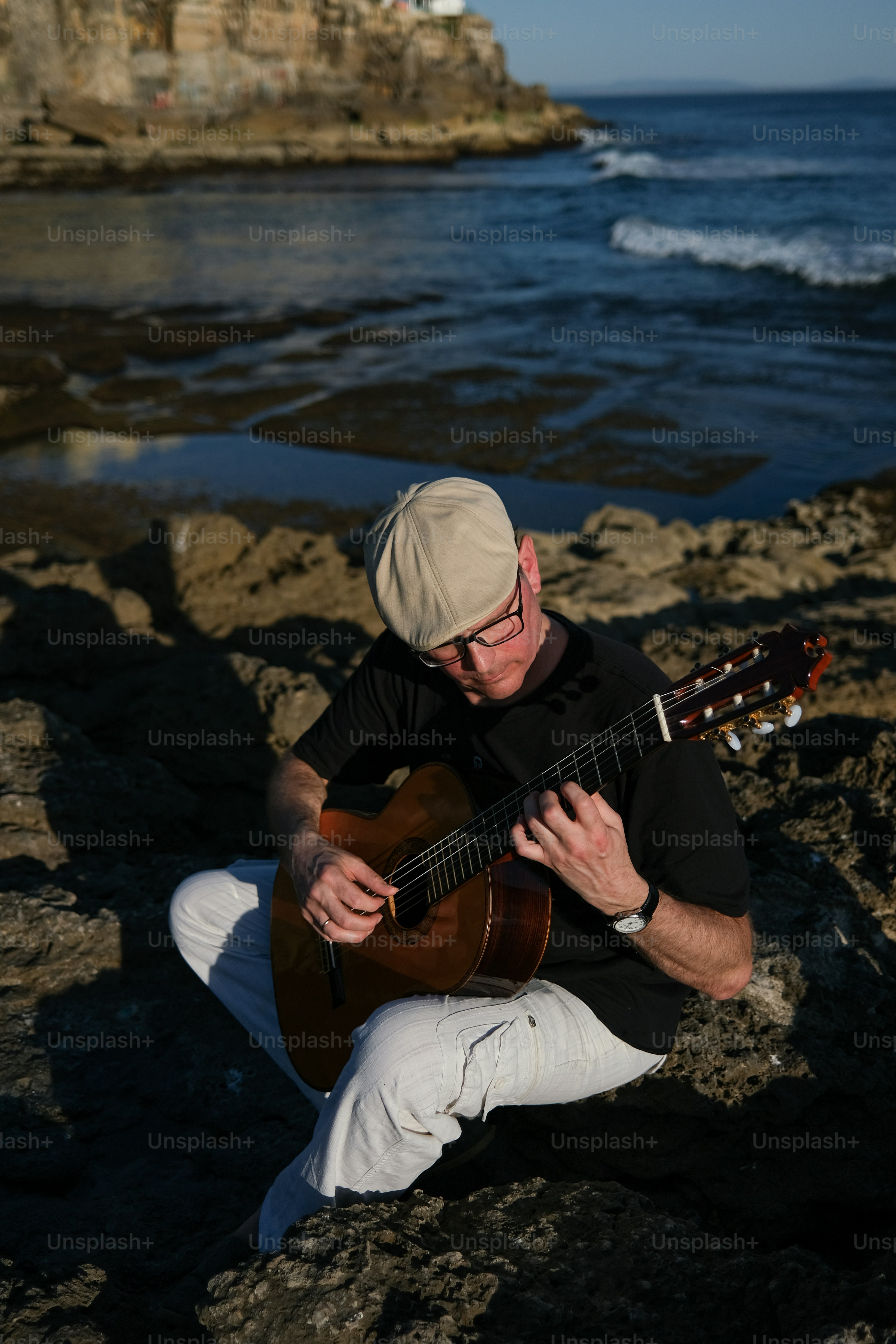 a man sitting on a rock playing a guitar