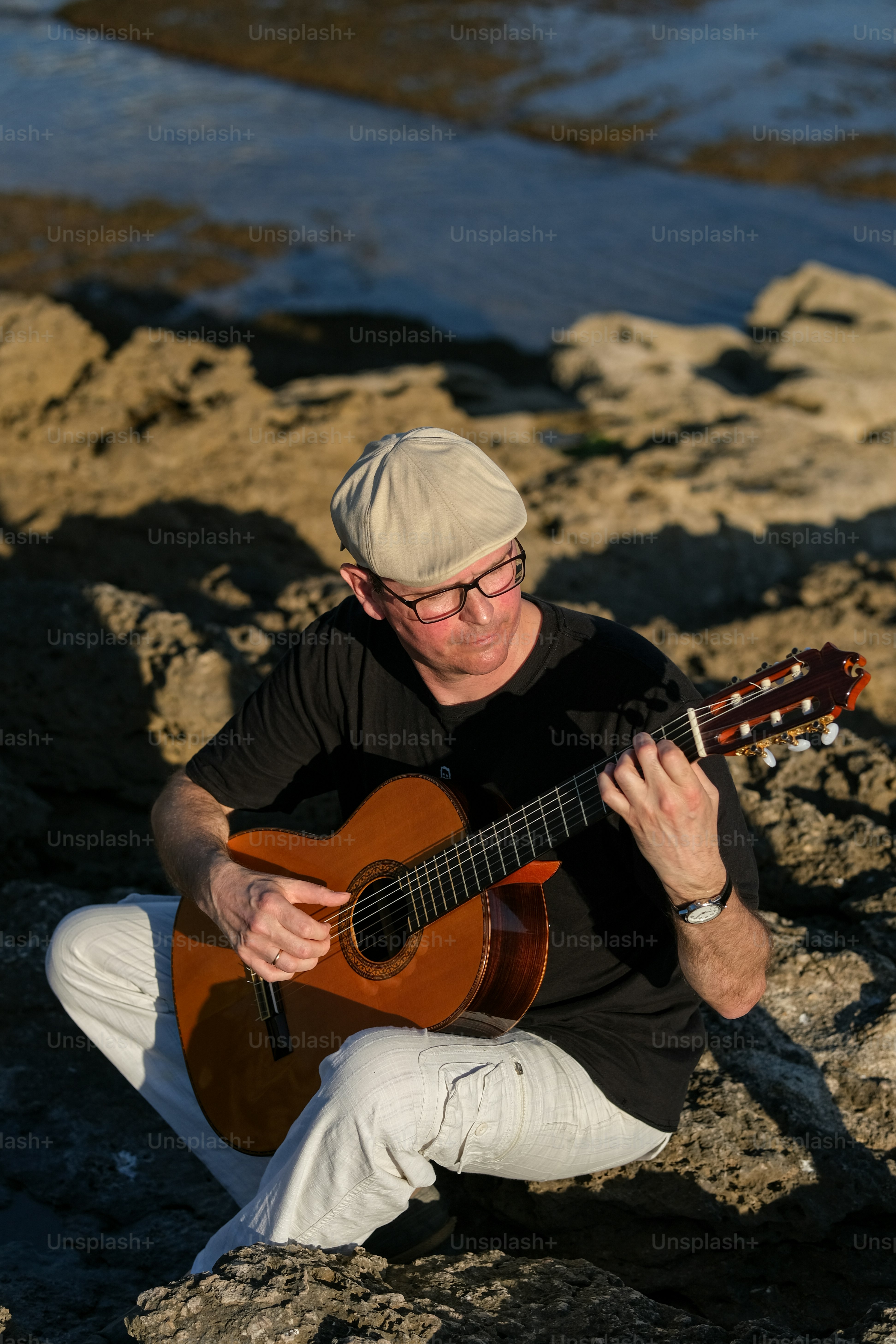 a man sitting on a rock playing a guitar