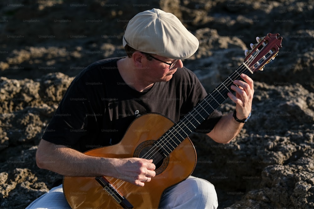 un uomo seduto su una roccia che suona una chitarra