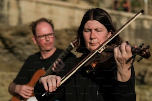 Una mujer tocando un violín mientras otro hombre toca una guitarra