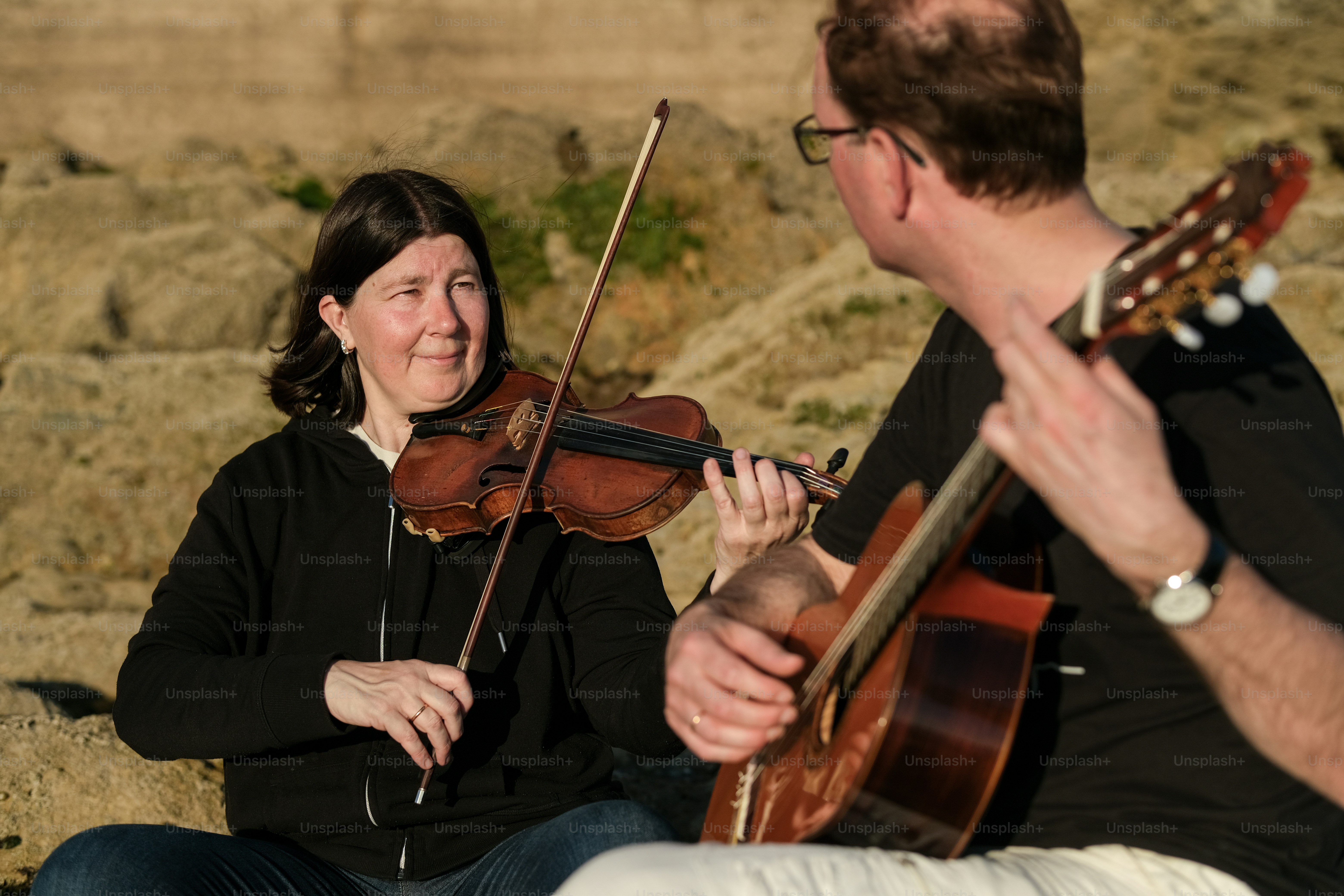 a man playing a violin next to a woman