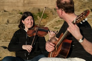 a man playing a violin next to a woman