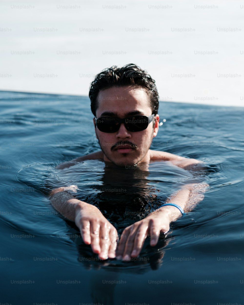 a man wearing sunglasses floating in the ocean