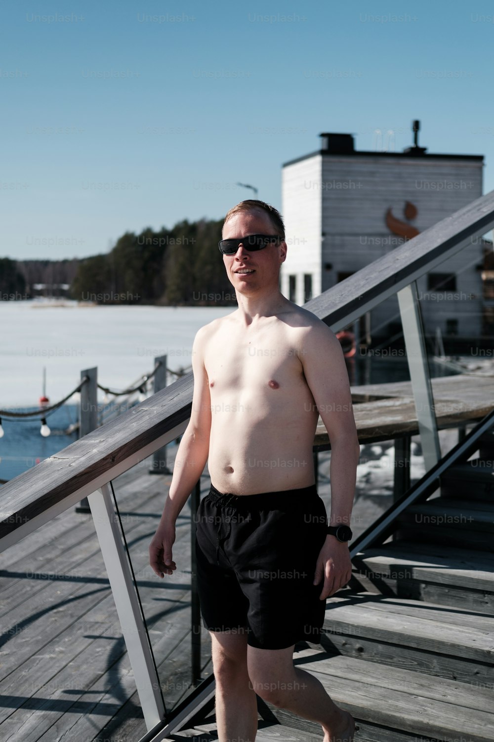 a man with no shirt standing on a dock