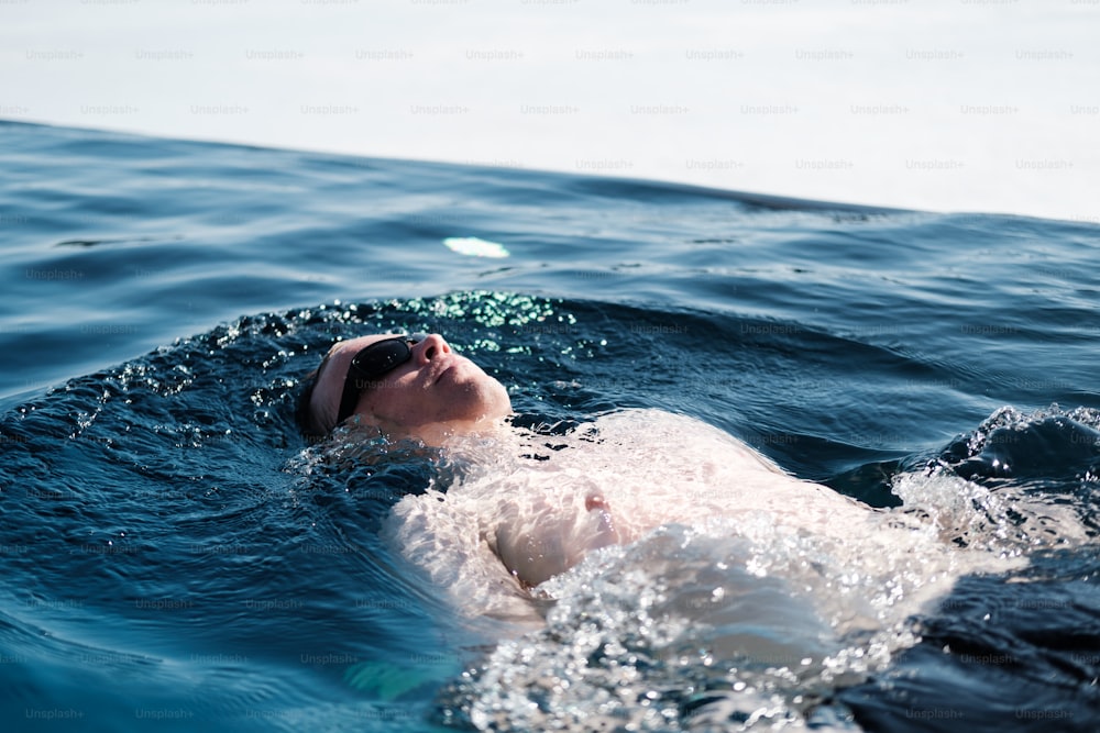 a man swimming in the ocean with his head above the water