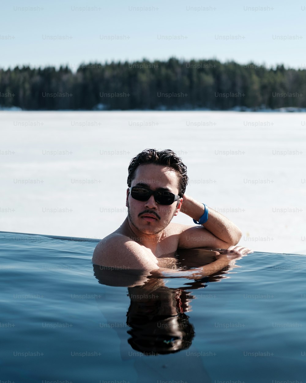 선글라스를 쓴 남자가 물속에서 수영하고 ��있다
