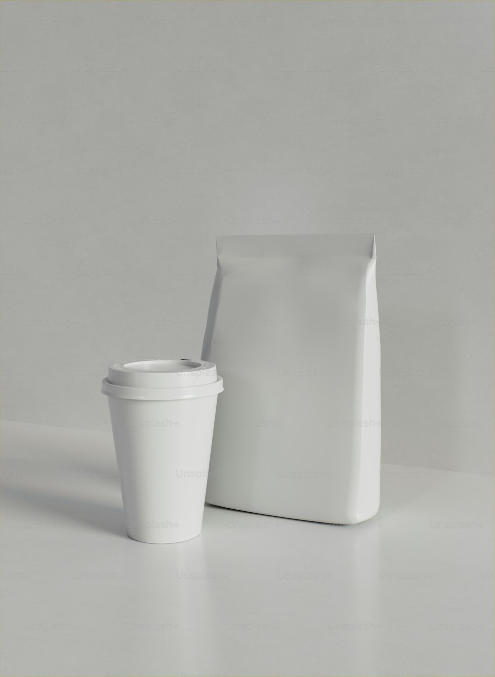 a white coffee cup next to a white bag