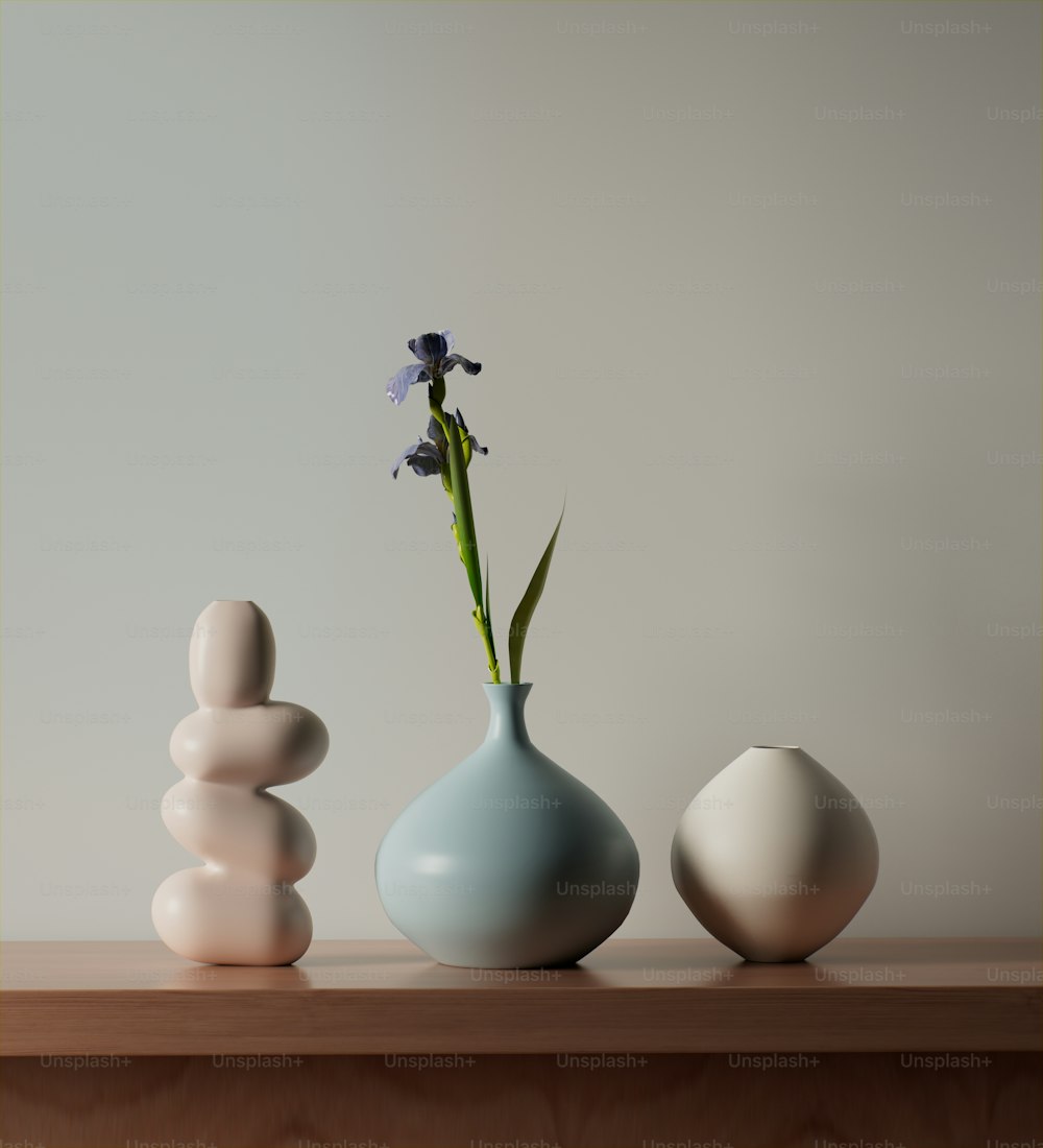 três vasos com flores neles sentados em uma mesa
