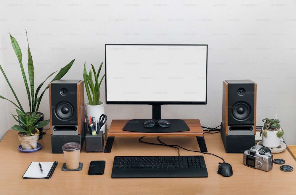 a desk with a monitor, keyboard and speakers