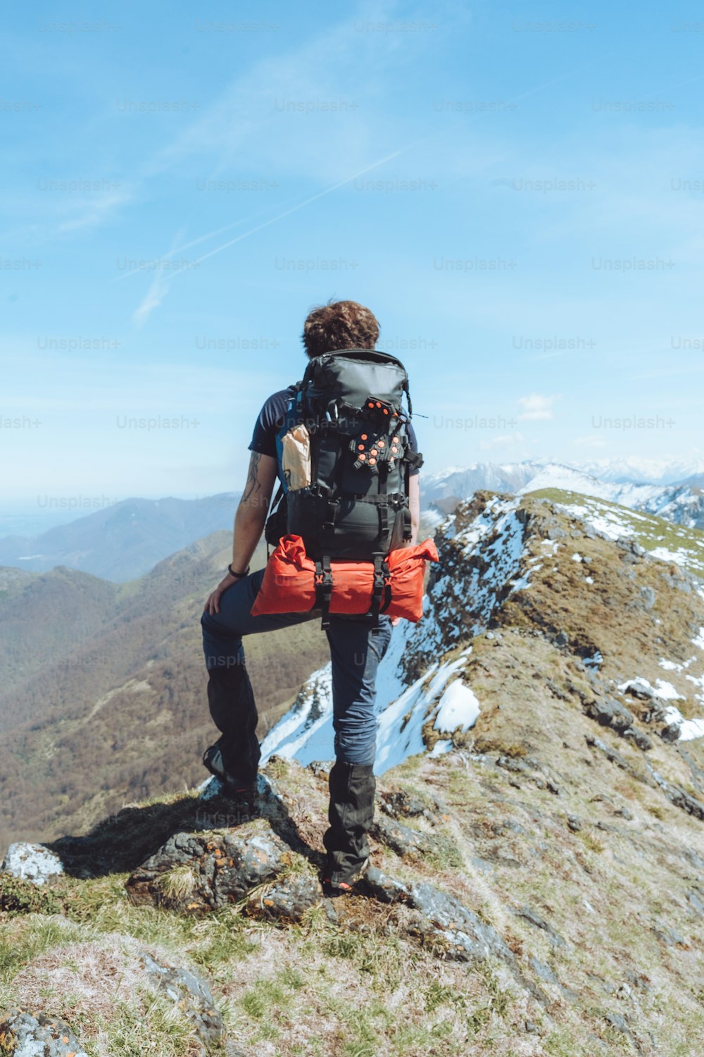 Ein Mann mit einem Rucksack sitzt auf einem Berg