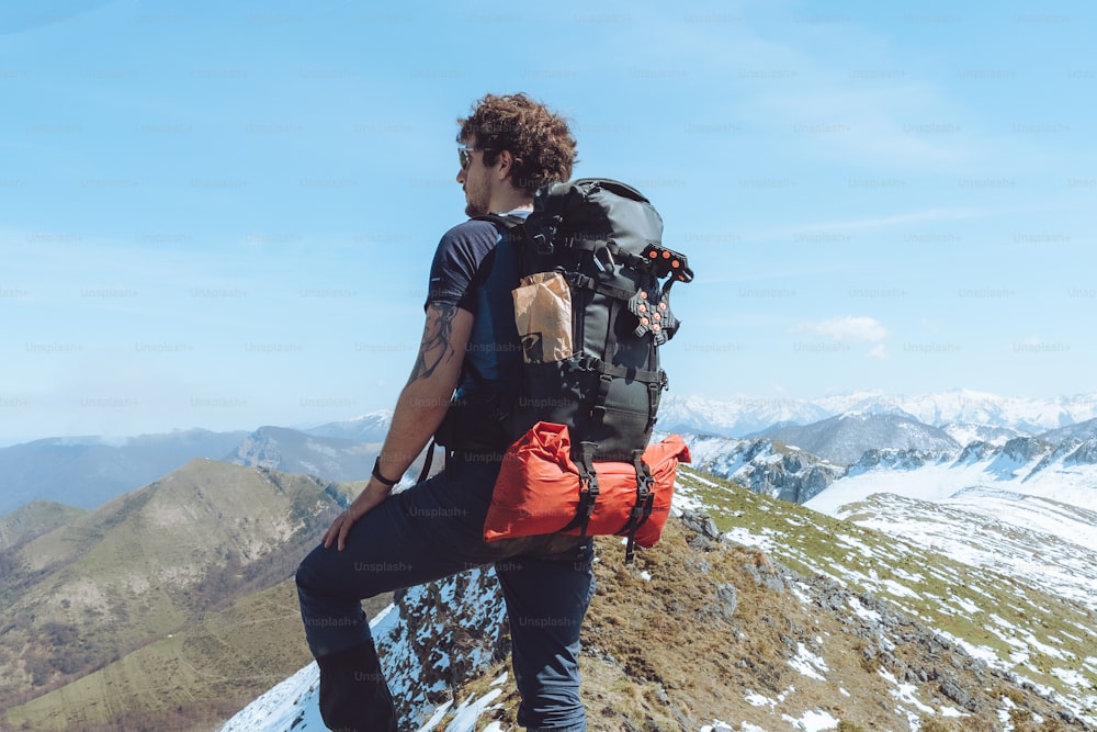 um homem com uma mochila no topo de uma montanha