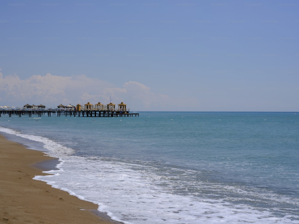 a beach with a pier in the distance