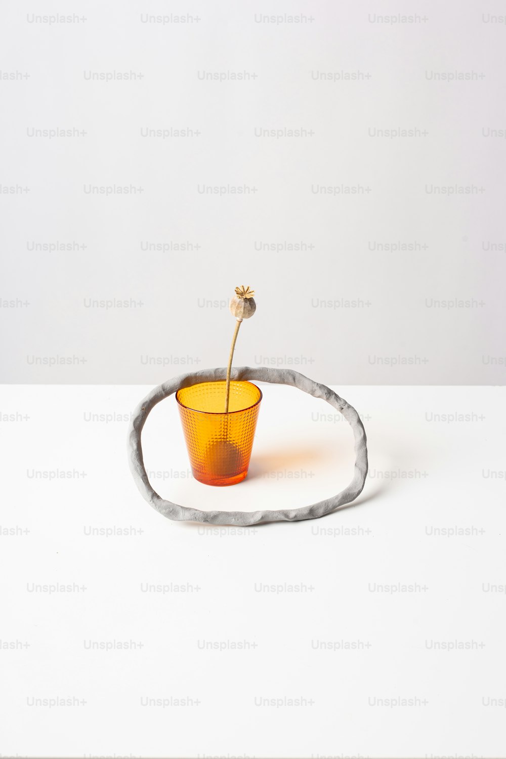 una piccola tazza arancione seduta sopra un tavolo bianco